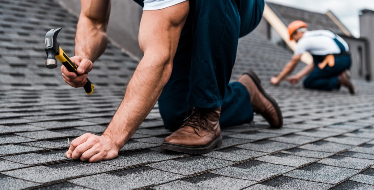 cropped view of repairmen in uniform working on rooftop